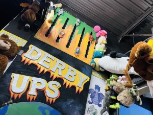 Derby Ups racing carnival game surrounded by oversized stuffed animales.