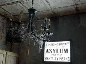 A cobweb covered chandelier in an old asylum.
