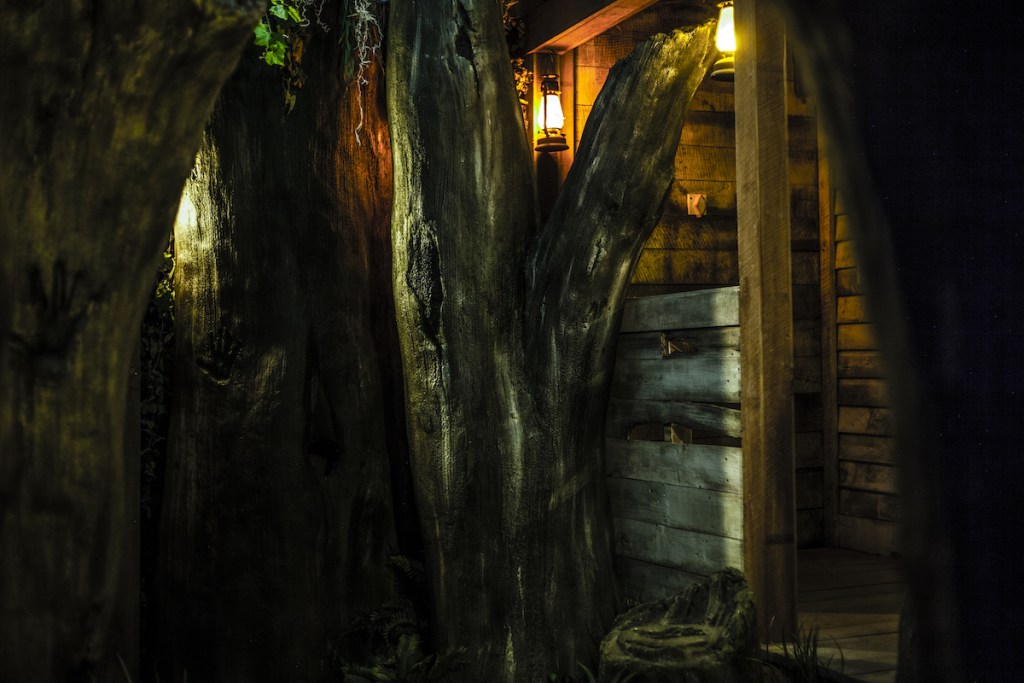 A large dead tree beside a wooden cabin.
