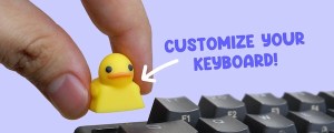Fingers placing a rubber ducky key cap onto a mechanical keyboard. Text reads, "Customize your keyboard."