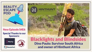 smiling man with curly short brown hair, wearing a survivor buff and necklace, and backpack, carrying a yellow tribe flag against greenery backdrop