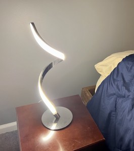 A vertical spiral lamp, one side is covered in LEDs, the other is metal.