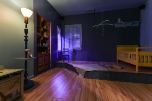 A child's bedroom with a yellow bed, bookshelf with toys, a blankey, and a book.