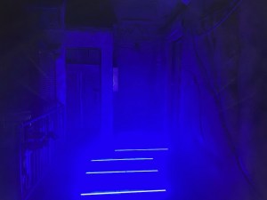 A dark mine with blue lights in the floor softly illuminating the area.