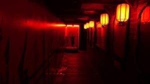 A long, dark walkway lit by red lanterns.