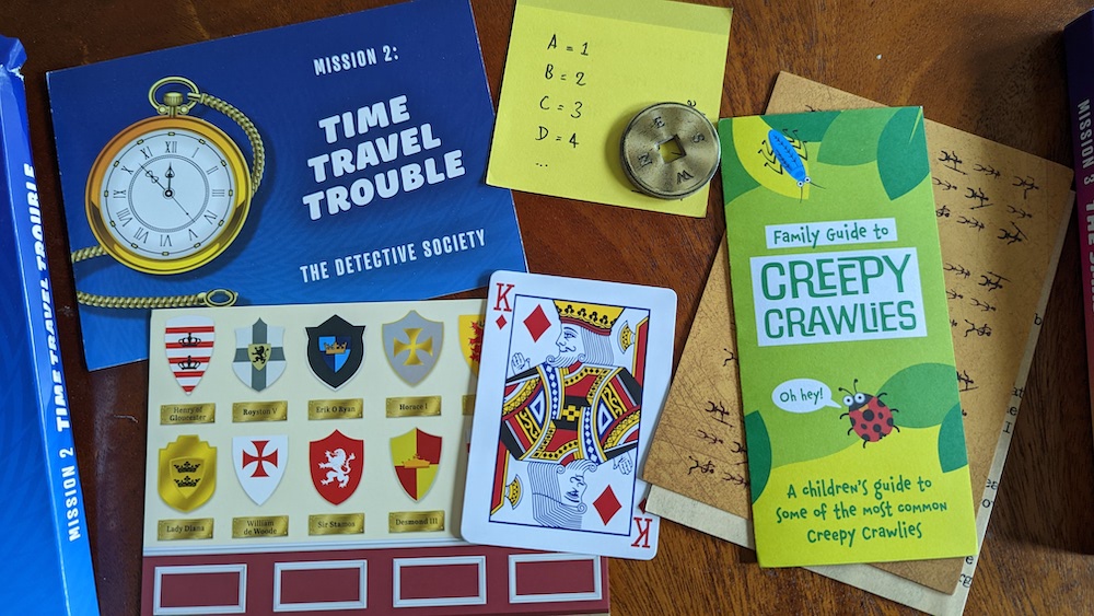 An assortment of colorful props including a compass a King of Diamonds, and some papers and booklets.