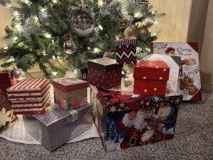 A pile of wrapped gifts under a Christmas tree.