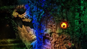 An enchanted forest with a small hut bearing a glowing window.