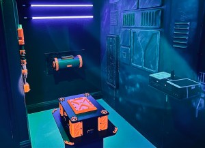 Black and orange 3D printed puzzle props in a futuristic black room.