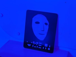 Closeup of a white, computer rendered face. A series of strange symbols are under it.