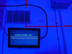 A computer screen with an upload indicator for the MASTERNET v9000 in a strake blue room.