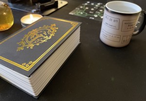 A box that looks like a book, beside a coffee mug with strange writing on it.