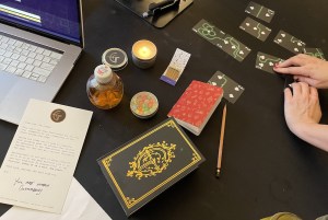 An assortment of puzzle components on a table with hands manipulating custom playing cards.
