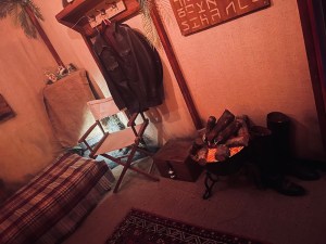 The inside of a canvas tent with a fire burning, an the clothing and artifacts of an adventurer.