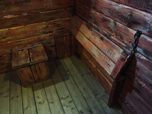 A wooden jail cell with a bench and a crate.