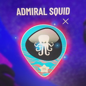 Closeup of a player icon & name at Level99. This is David's Admiral Squid lvel 115 with a squid icon and sparking particle effects.