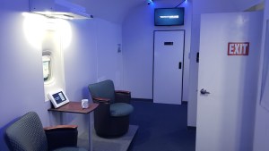 A pair of chairs beside an exit door in a stark white passenger plane.