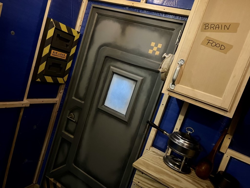 The metal door to a kitchen in an arctic research facility . A cabinet is labeled "BRAIN FOOD."