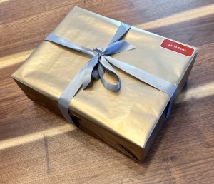 A package addressed to David & Lisa wrapped in silver paper with a silver bow.