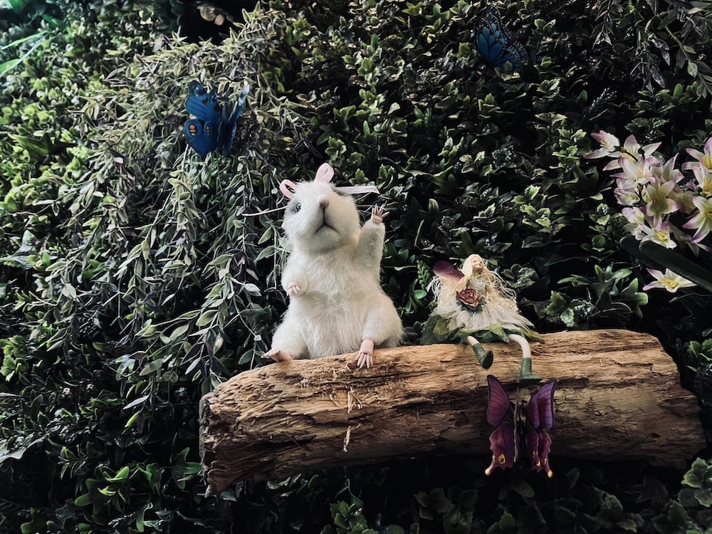 A little mouse sitting beside a fairy on a branch in a tree.