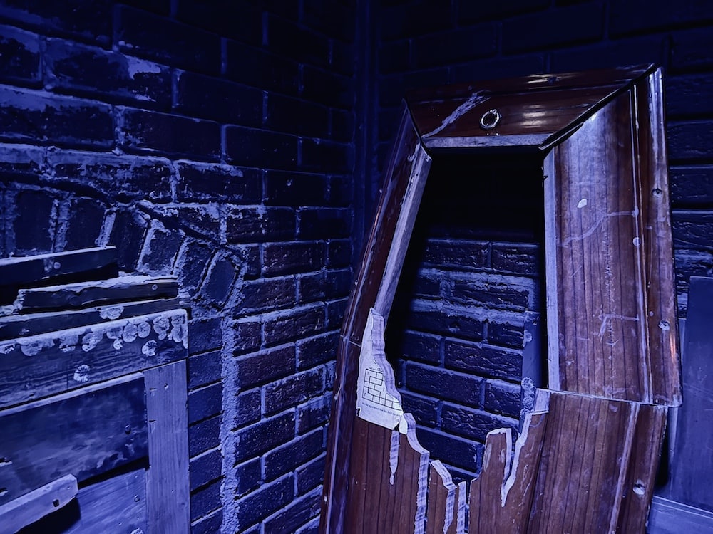 Closeup of a damaged coffin. A large hole has been punched into it and the coffin is empty.