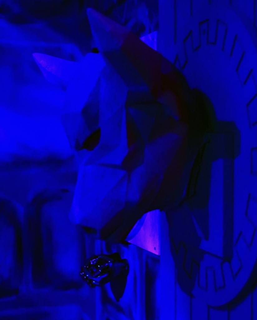 A statue of a dog's head mounted to the wall bathed in blue light.