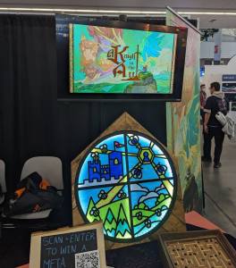 A Knight in the Attic booth with a stained glass display and some games.
