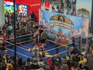 A wrestling ring with wrestles performing to promote the game Wrestle Quest.