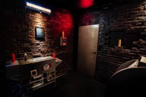 Back alley with a hot dog cart, and an ATM, an illuminated sign that reads, "HOT DOGS = LIFE" and many condiment bottles.