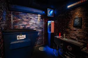 Back alley with a dumpster, a hot dog cart, and a payphone.