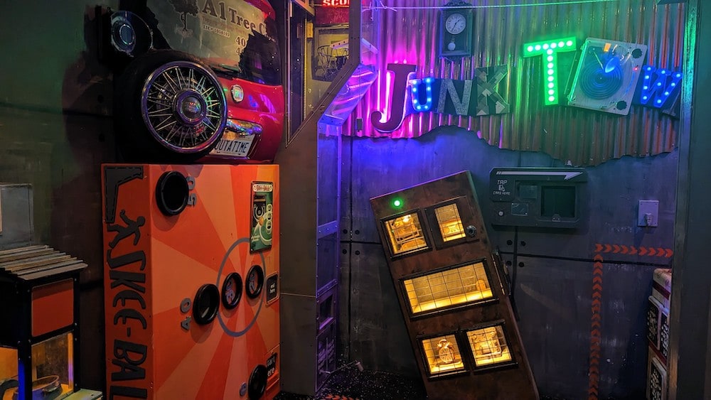 A large room filled with technology from various decades. The wall is labeled, "Junk Town" using letters from farious discarded signs.