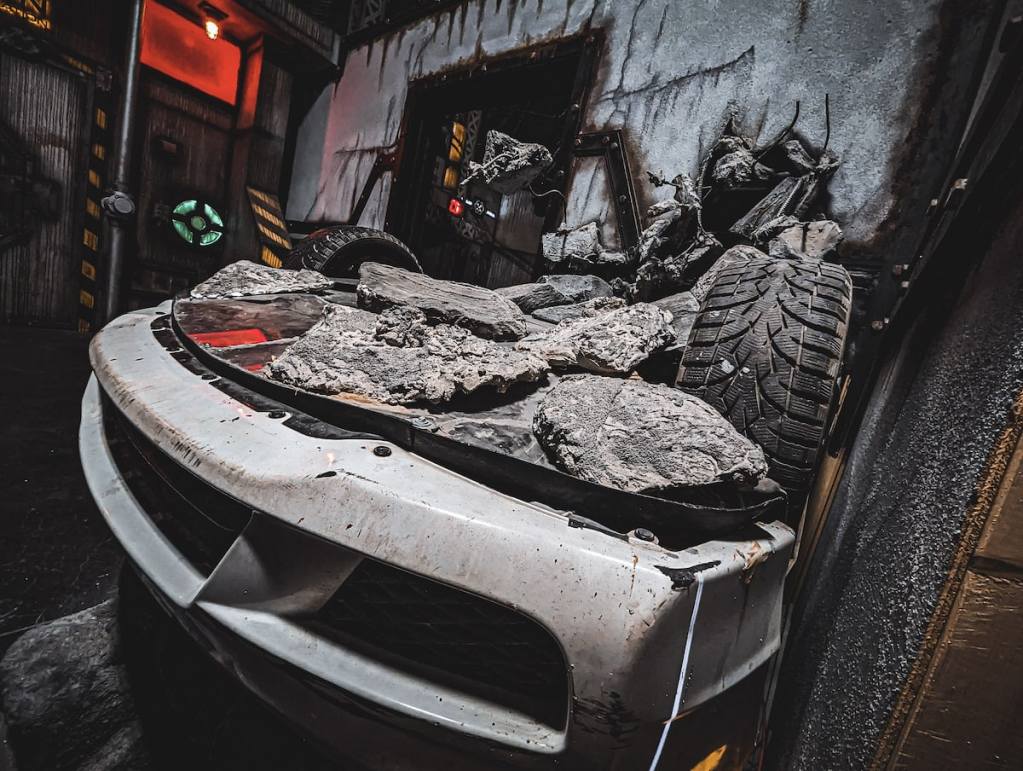 An upside down car crashed through a wall of a building.