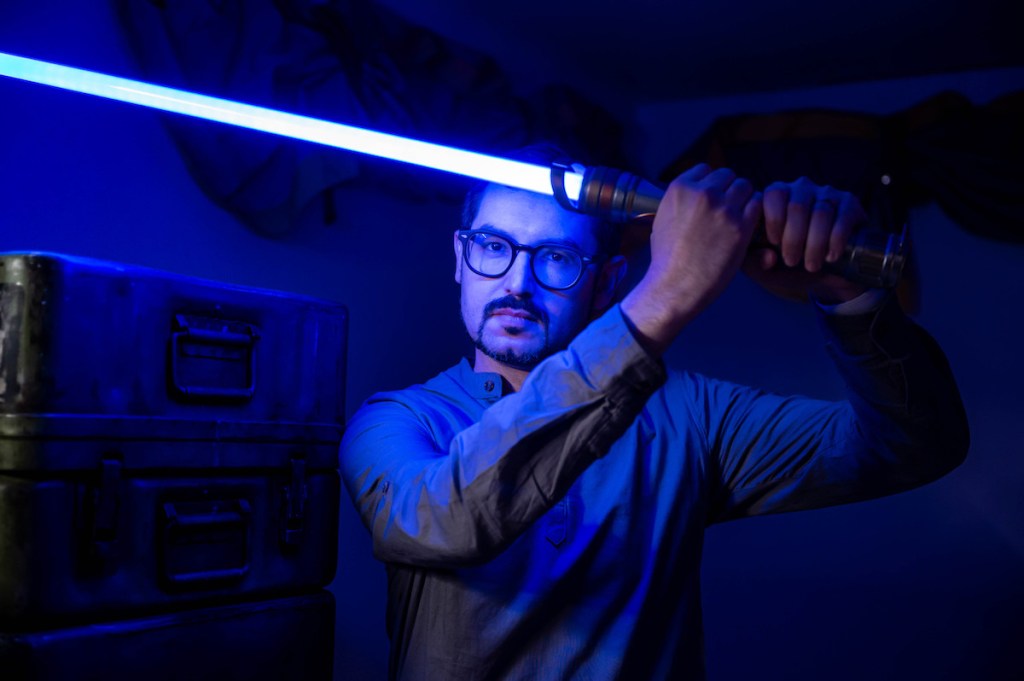 David holding up a blue lightsaber in a defensive posture.