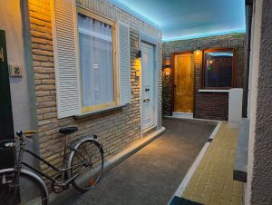 A narrow street flanked by apartments. A bicycle leans against one fo the units.
