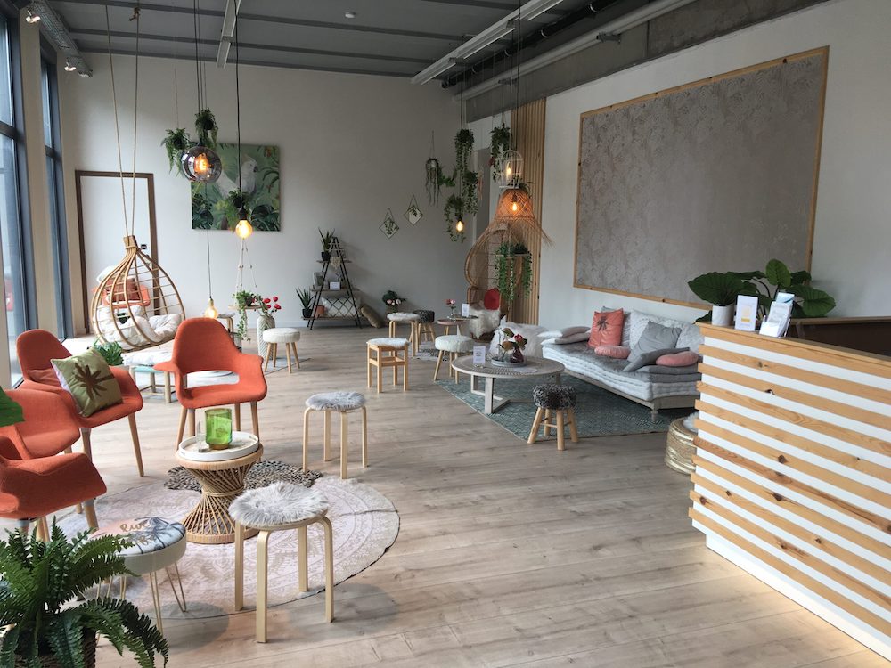 A large, comfortable looking lounge filled with pillows and seating. It has a deliberate color scheme with whites, grays, oranges, and greens.