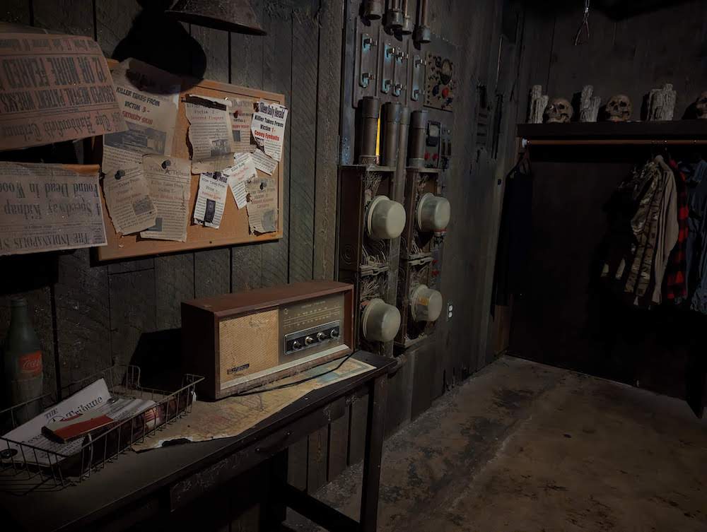 An assortment of dusty power meters on the wall of a dingy cellar. In the distance skulls and candles rest on a shelf.