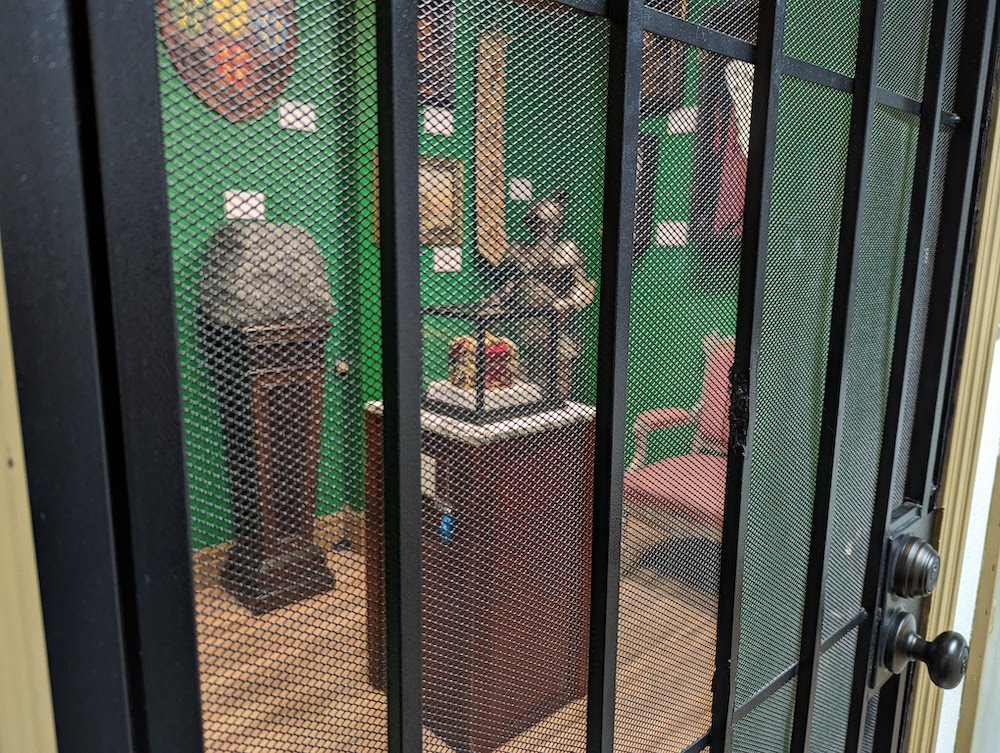 View of an art collection through a gate. In the middle of the room is a crown in a display.