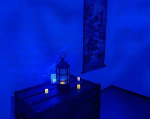 A blue lit space with a trunk that has an assortment of LED candles resting atop it.