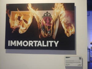 Photo of a screen promoting the game Immortality at Tribeca 2023 depicts a series of posters burning.