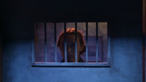 a women looks through the bars of a jail cell