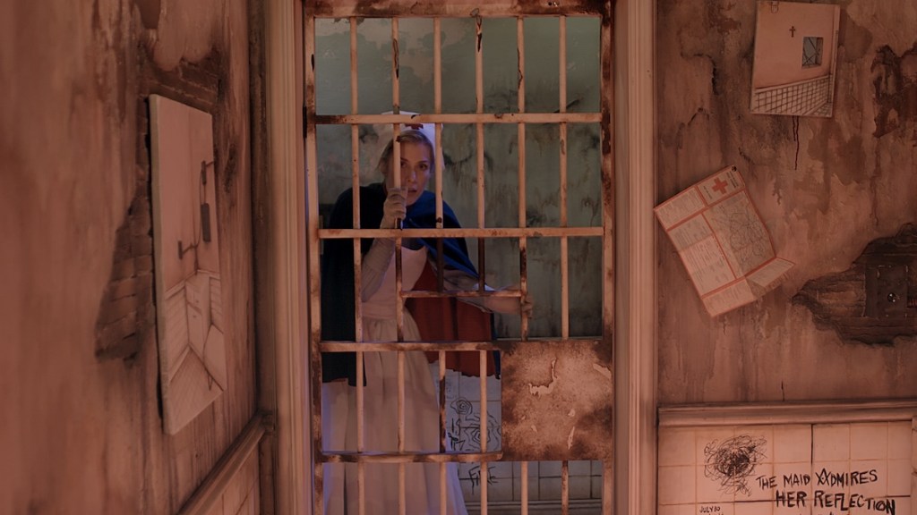 a nurse looks through the bars into an asylum cell