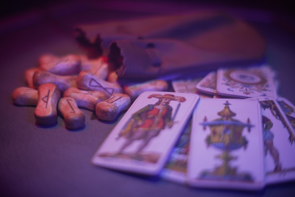 a pile of bones with rune symbols next to a pile of tarot cards