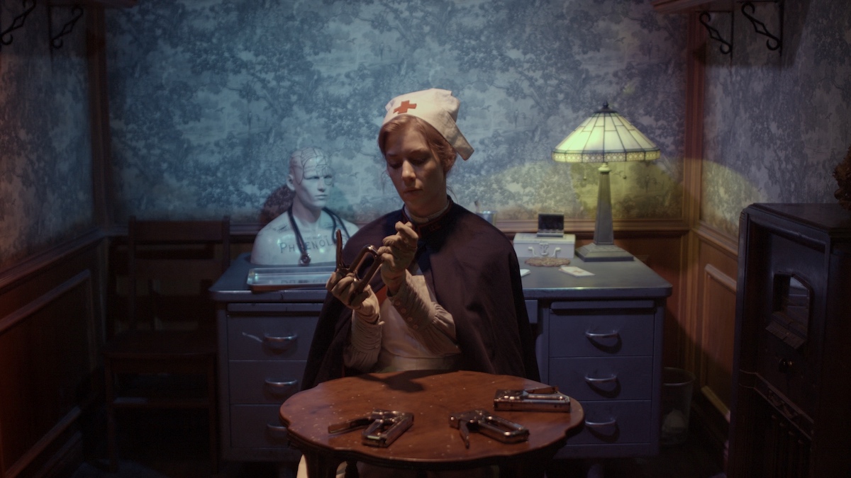 a nurse stands in a study in front of a table with stapler guns set upon it
