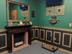 An elegant room with green and brown walls with gold trim and a fireplace.