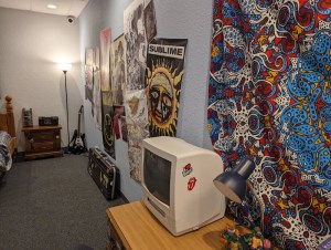 A bedroom with a cobination TV and VHS, and posters from 90s bands like Sublime and Nirvana.