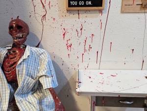 A bloodied skeleton in a button up shirt surrounded by blood spatter.