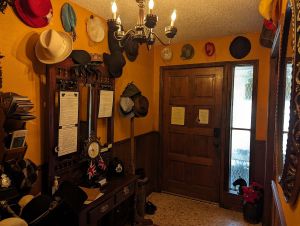 Mud room of a home with hats hanging from the wall and coatrack.