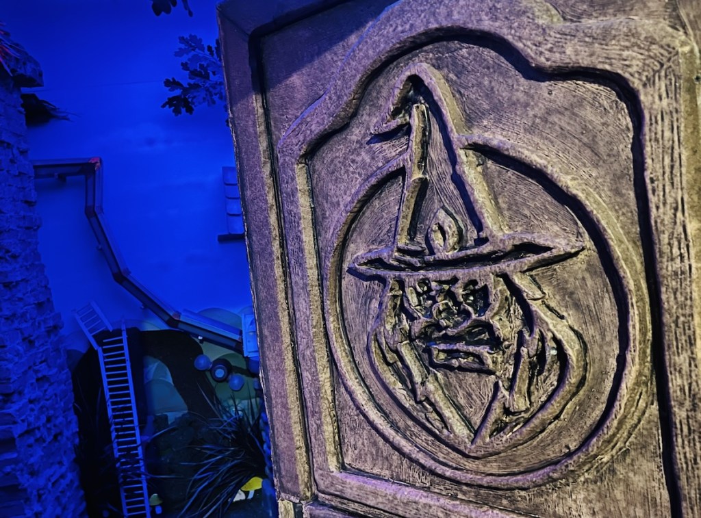A stone door with the carving of a wizard on it.