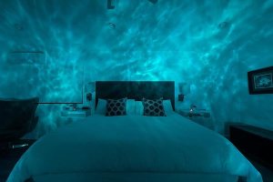 A bedroom illuminated with a soft, nebula-like green projection on the walls.
