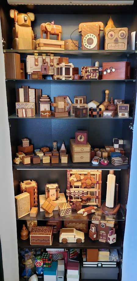 Shelf full of mechanical wooden puzzles, about 10-15 on each shelf.